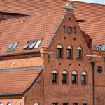 Red brick facade of a historic building in Gdańsk, Poland with intricate roof design.