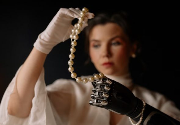 A woman with a prosthetic hand gracefully holding a pearl necklace, showcasing elegance and modern technology.
